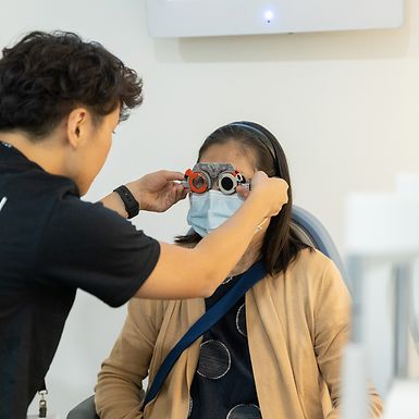 person giving eye exam to woman in eye doctor chair